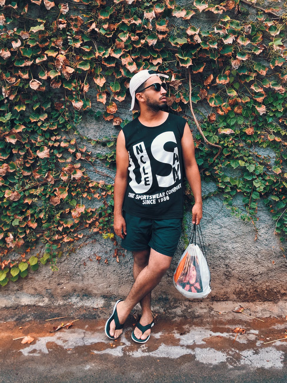 man standing near wall with vines